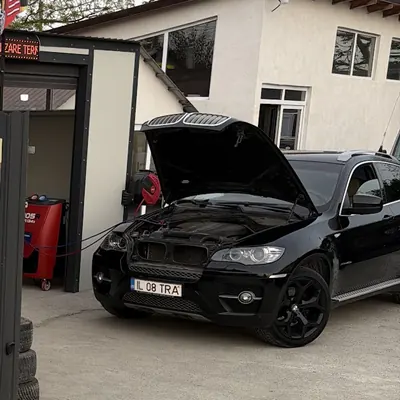 Stația roșie de încărcare freon din curtea service-ului, conectată la un SUV negru